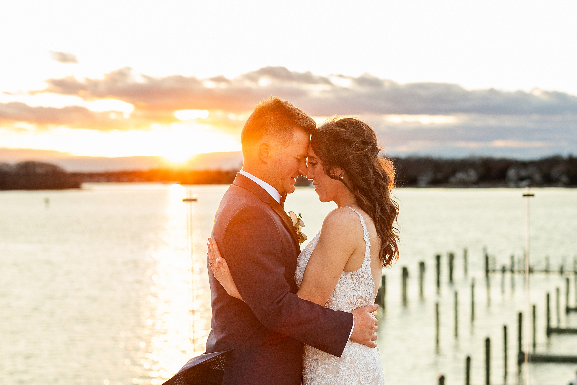 bride and groom hug at sunset on dock at Clarks Landing Yacht Club