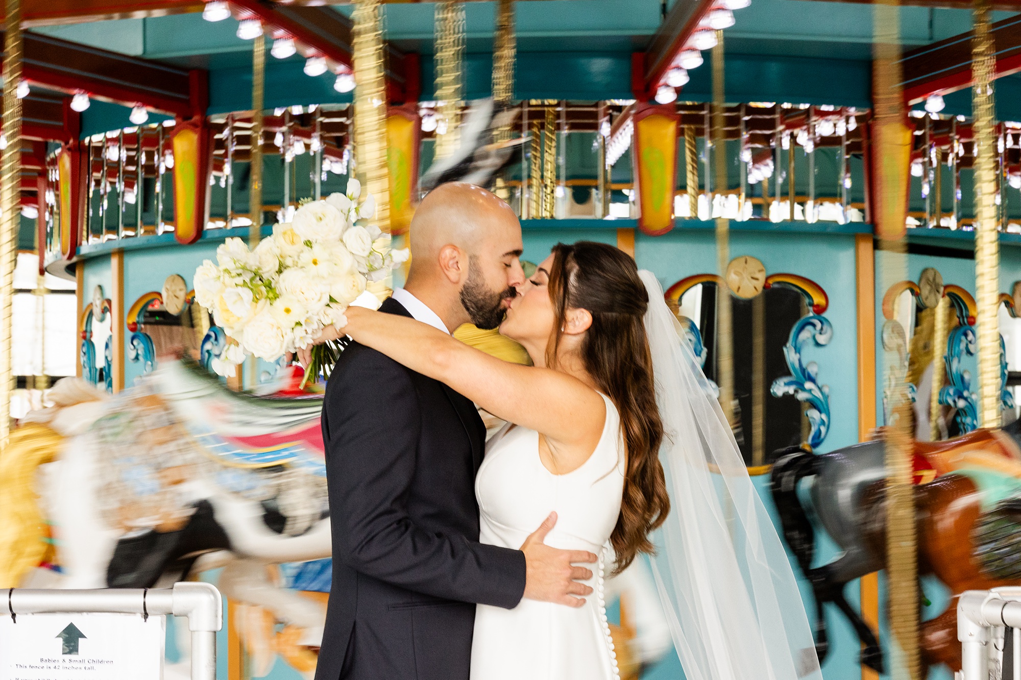 bride and groom kiss on carousel in New Jersey